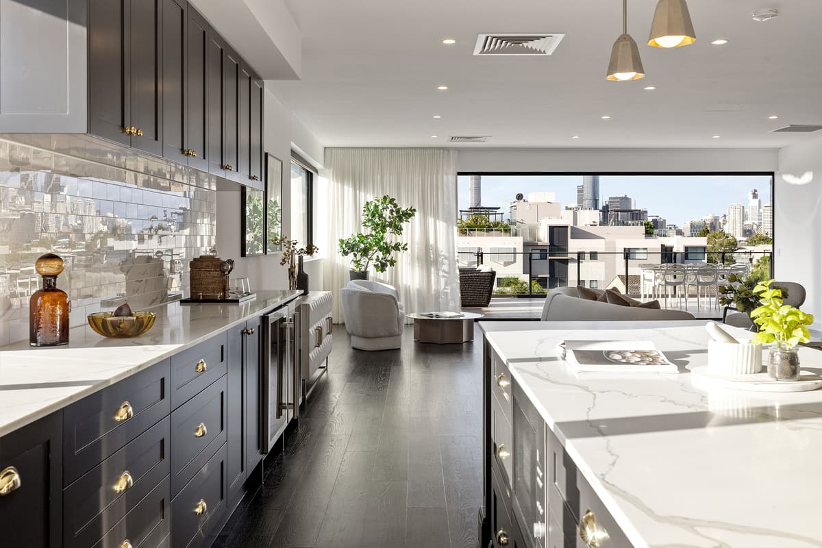 Bright modern kitchen and living area with dark cabinetry, marble counters and a city view through large windows
